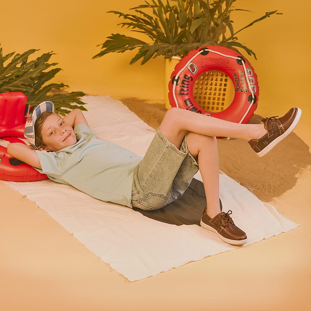 Niño usando calzado infantil Coqueta y Audaz tipo mocasín de piel color café, diseño casual, cómodo y resistente, ideal para primavera verano y actividades al aire libre.