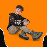 Niño usando botas Coqueta y Audaz color verde con ajuste de agujeta, para la campaña Black Days. Calzado resistente y cómodo con descuentos especiales.